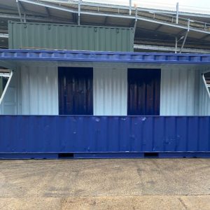 20ft “Dug Out” Football Stand - A 20-foot second-hand shipping container converted into a football spectator stand, featuring a design in white, blue, and green colours.